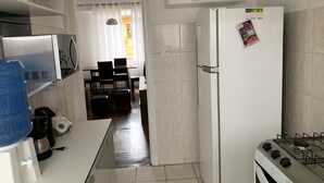 A compact kitchen with a refrigerator, stove, and a water dispenser.