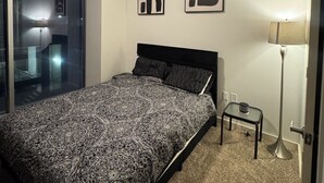 A bedroom with a bed, a floor lamp, and two abstract wall art pieces.