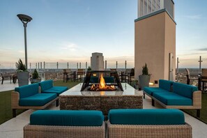 Una terraza en la azotea con una chimenea, mobiliario exterior y vistas del horizonte de la ciudad.