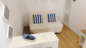 A small, well-lit room with a bed, a bedside table, and a wall with three framed pictures. - Your beach house in Sicily, Casa Sciàpò (Terrasini)