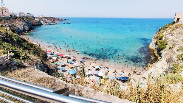 A beach with clear blue water, rocky cliffs, and umbrellas. - Your beach house in Sicily, Casa Sciàpò (Terrasini)