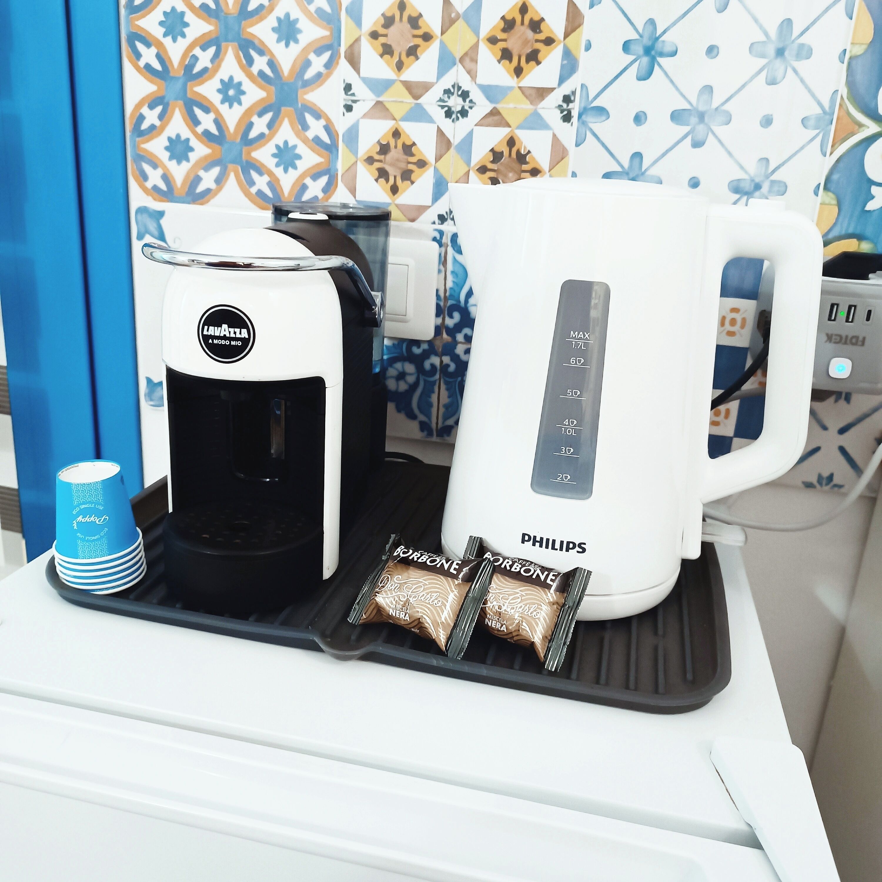 Kaffemaskine og elkedel på en bordplade med et mønstret bagpanel.