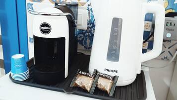 Kaffemaskine og elkedel på en bordplade med et mønstret bagpanel.