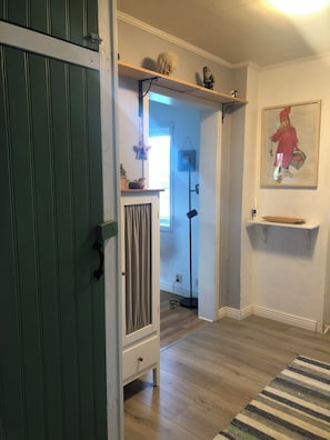 A room with a wooden floor, a striped rug, a white dresser, a green door, and a painting on the wall. - Villa Indalsälven (Hammarstrand)