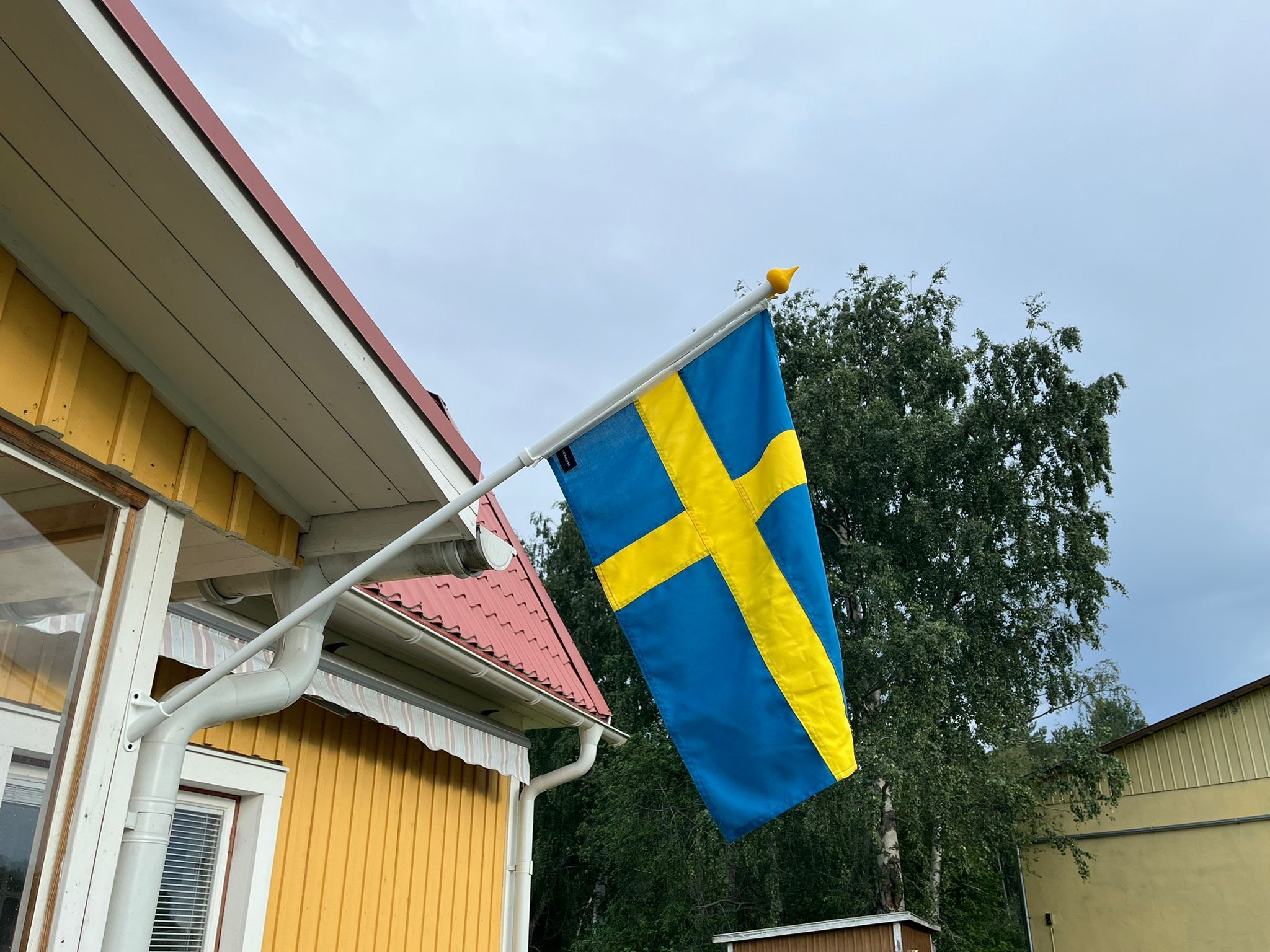 A flagpole with a flag, a red roof, and a window.