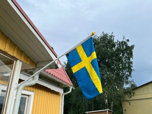 A flagpole with a flag, a red roof, and a window. - Villa Indalsälven (Hammarstrand)