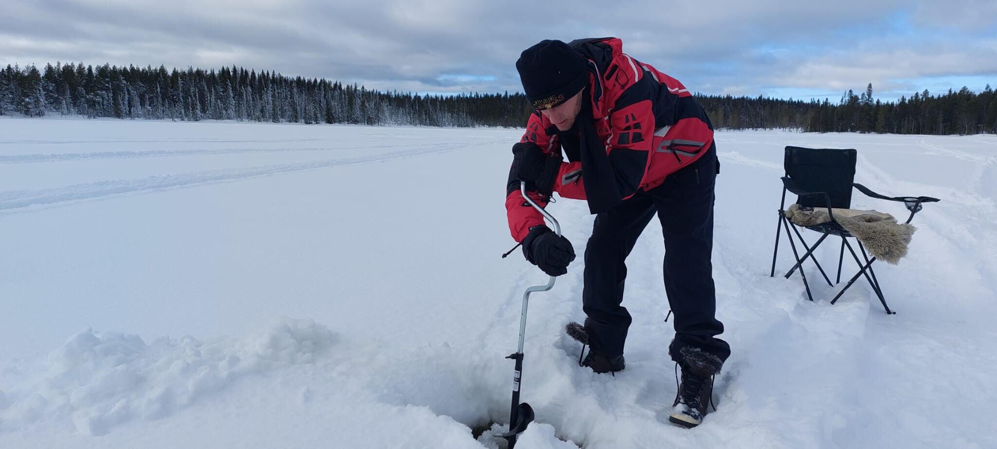 A person in winter gear using a metal tool on the snow.
