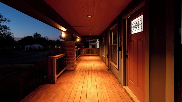 Eine hölzerne Veranda mit Backsteinwand und Holzgeländer.