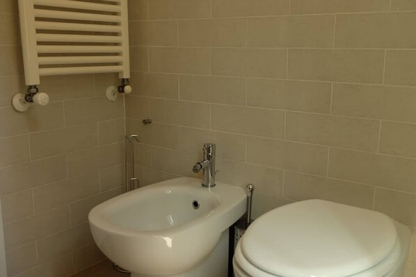 Ein Badezimmer mit einer Bidet-Funktion, Toilette und Handtuchhalter.