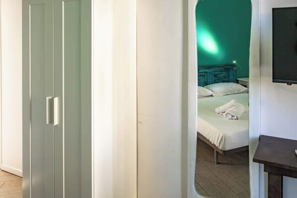 A bedroom with a bed, a nightstand, a TV, and a wardrobe.