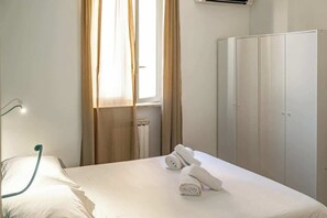 Une chambre d’hôtel avec un lit, un radiateur, une armoire et une fenêtre avec des rideaux.