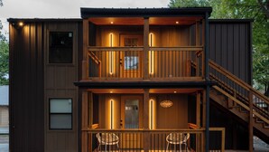 A two-story wooden building with a balcony, a staircase, and a door with a window. - Modern Cabin  Mins from TU, Downtown, Expo, St John and HIlcrest - upstairs (Tulsa)