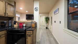 A modern kitchen with wooden cabinets, a black stove, and a coffee bar. - Modern Cabin  Mins from TU, Downtown, Expo, St John and HIlcrest - upstairs (Tulsa)