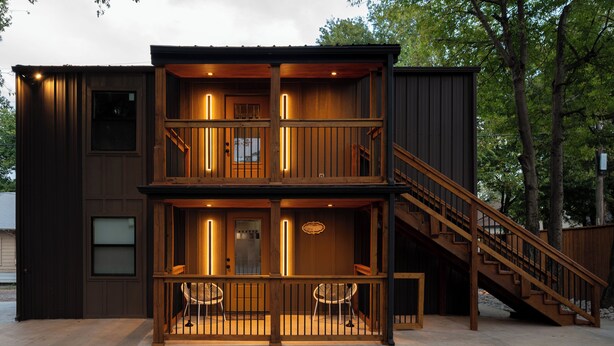 A two-story wooden building with a balcony, a staircase, and a small outdoor seating area. - Modern Cabin  Mins from TU, Downtown, Expo, St John and HIlcrest - upstairs (Tulsa)