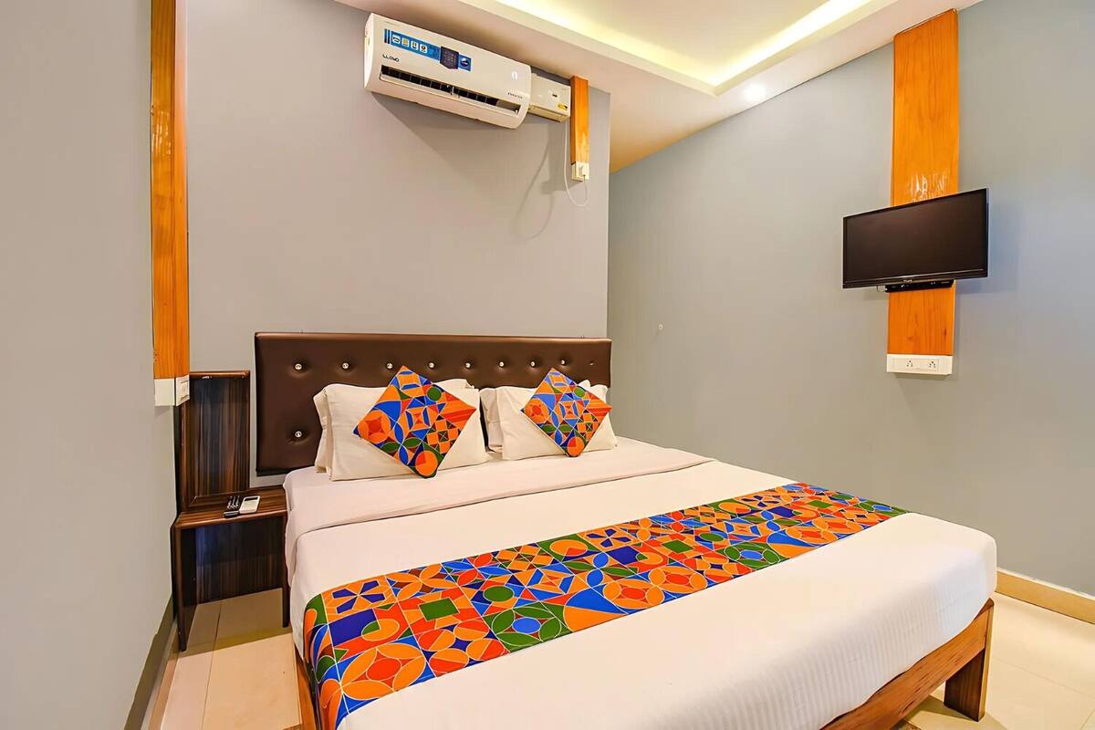 Une chambre d’hôtel avec un lit, un téléviseur fixé au mur et un appareil de climatisation placé au-dessus du lit.