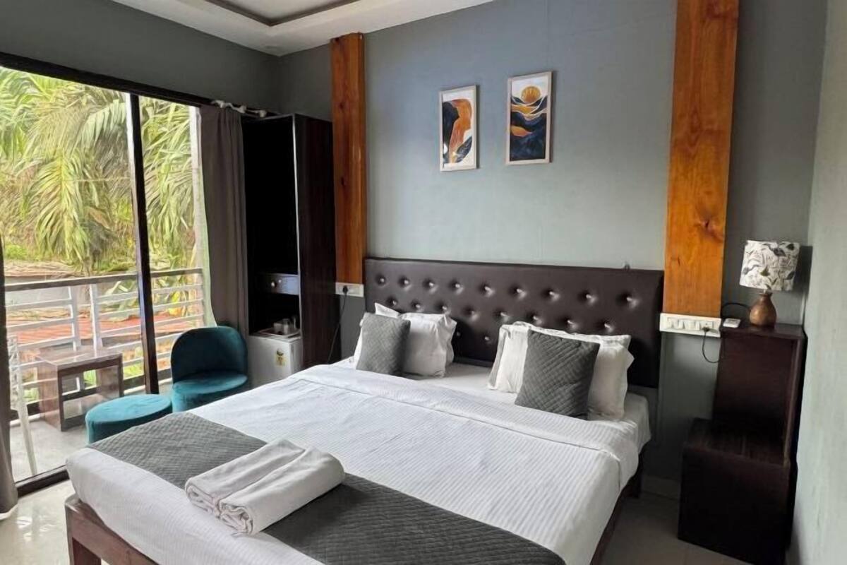 Une chambre d’hôtel avec un grand lit, une chaise, une table de chevet et une vue sur la verdure.