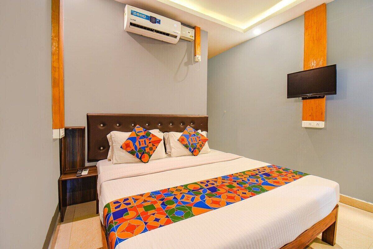 Une chambre d’hôtel avec un lit, un téléviseur fixé au mur et un appareil de climatisation placé au-dessus du lit.