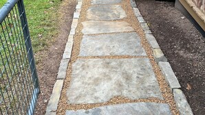 A stone pathway leading to a wooden deck with a metal railing.