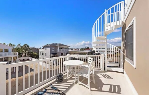 A balcony with a white railing, a small table, and two chairs. - Beautiful Long Beach Island Getaway - Steps from the beach! (Long Beach)