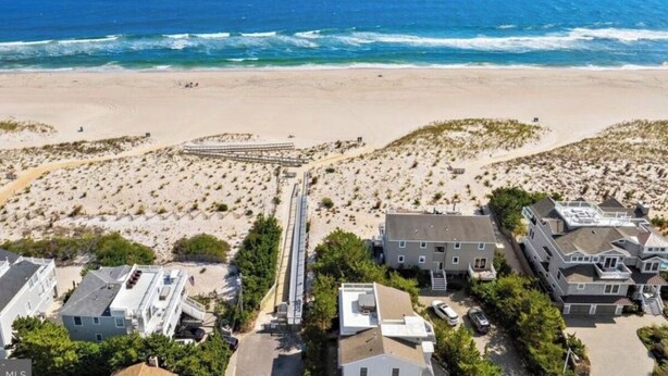 Vista aérea de una comunidad frente al mar con casas, un paseo marítimo y el océano.