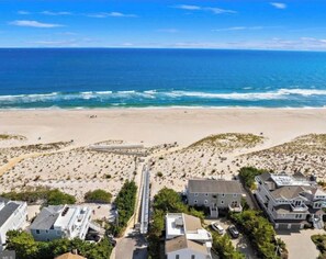 An aerial view of a beachside community with houses, a boardwalk, and the ocean.