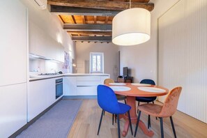 A modern kitchen with white cabinets, a central island, and a dining area with a round table and chairs.