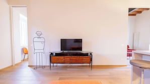 Ett modernt vardagsrum med trägolv, en tv på ett tv-bord och en minimalistisk inredning.