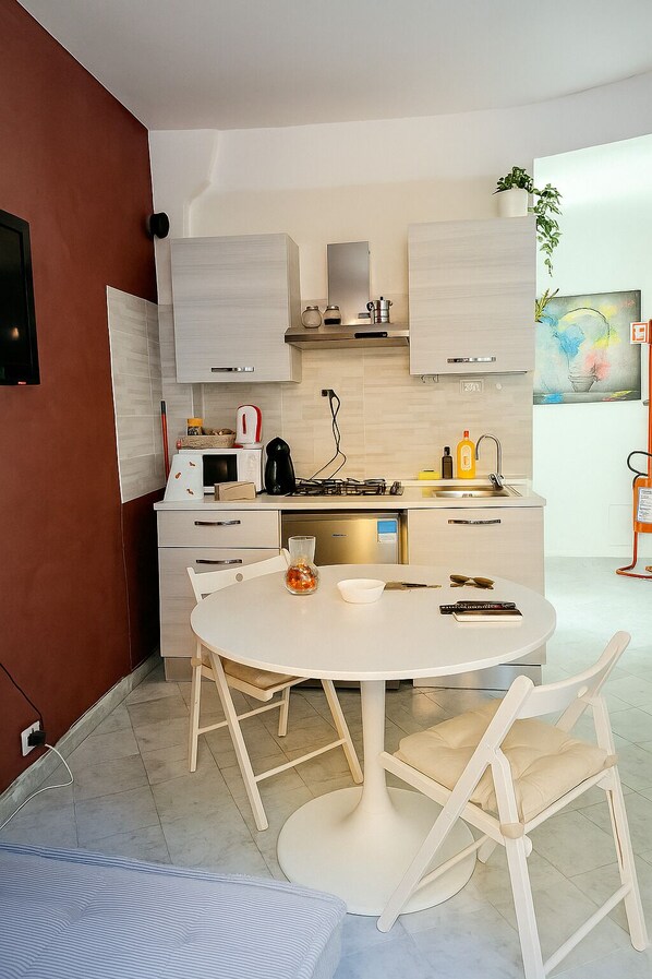 A modern kitchen with white cabinetry, a round dining table, and two white chairs.
