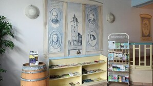 Eine Bibliothek mit Bücherregalen, einem Porträt-Wandgemälde und einem Informationsstand.