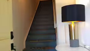 Eine Treppe mit Teppich und einer weißen Wand mit einer schwarzen Lampe.