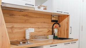 A compact kitchen with white cabinets, a wooden countertop, a dishwasher, and a sink.