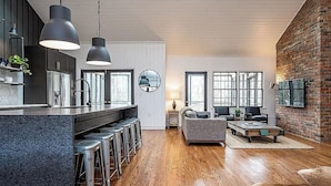 A modern kitchen with a bar area, wooden floors, and a living room with a fireplace.