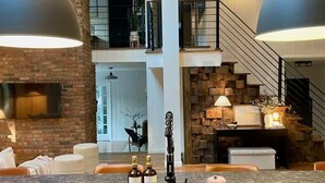 A modern kitchen with a central island, pendant lighting, and a stone fireplace.