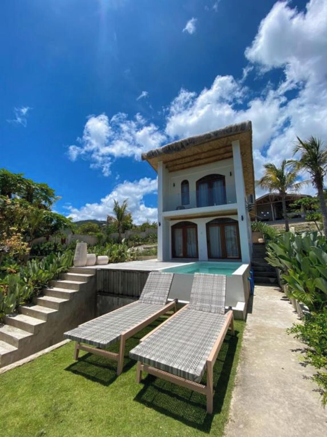 A two-story house with a swimming pool, outdoor seating, and a garden.