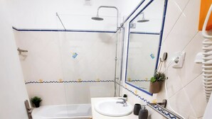 Ein kleines Badezimmer mit einer Badewanne, einem Waschbecken und einem Spiegel.