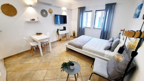 Ein modernes Schlafzimmer mit Bett, Nachttisch, Sessel, Schreibtisch und Fernseher.