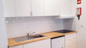 Eine kompakte Küche mit weißen Schränken, einer Holz Arbeitsplatte, einem integrierten Geschirrspüler und einem Edelstahl-Spülbecken.
