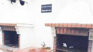 Ein Küchenbereich im Freien mit zwei Backöfen aus Ziegeln, einem Spülbecken und einem Schild mit der Bitte um Reinigung nach Gebrauch.