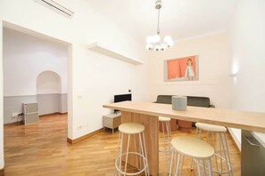 A modern kitchen with a wooden countertop, bar stools, and a hanging light fixture. - BuddyRent - Dadada - Trevi - 8 ospiti (Roma)