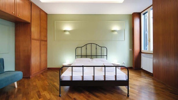 Ein Schlafzimmer mit einem Bett, Holzwänden, einem blauen Sessel und einem Fenster.