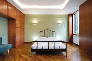 A bedroom with a bed, wooden walls, a blue chair, and a window. - BuddyRent - Dadada - Trevi - 8 ospiti (Roma)