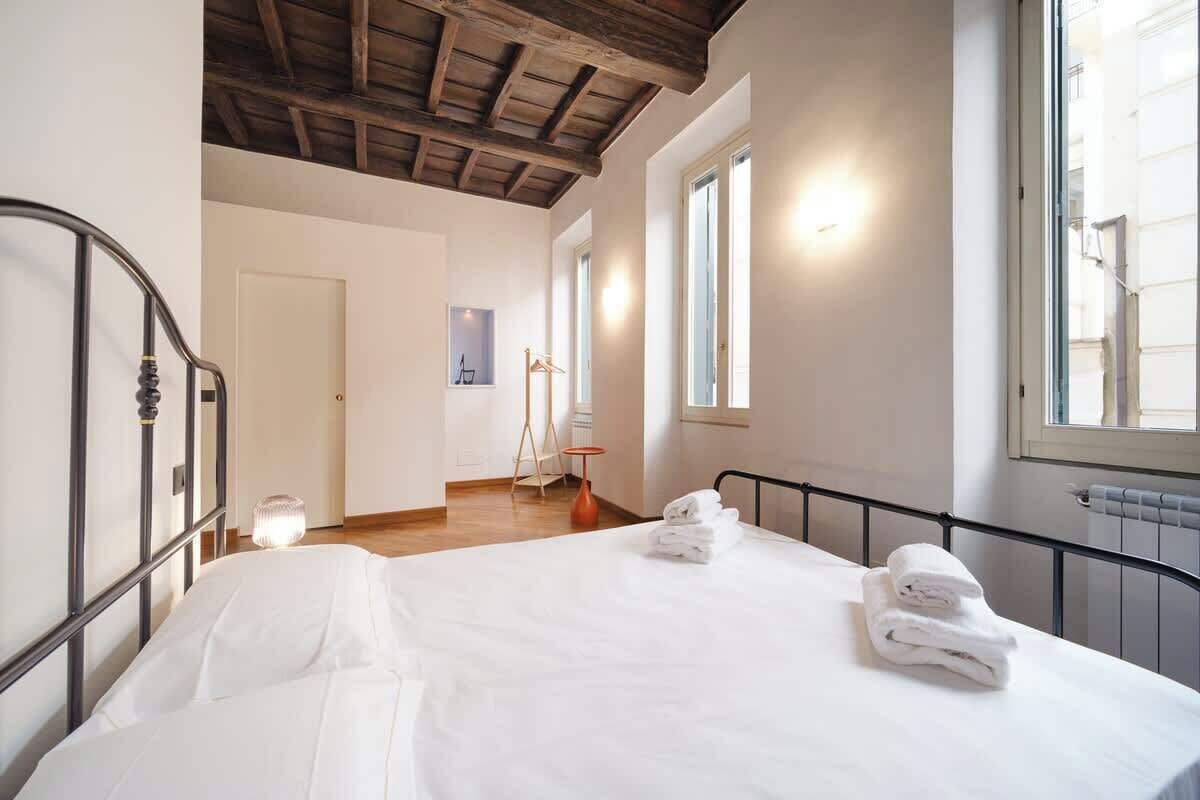 A bedroom with a bed, a wooden ceiling, a window, and a door.