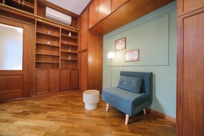 A room with wooden cabinetry, a blue sofa, and a white round ottoman.