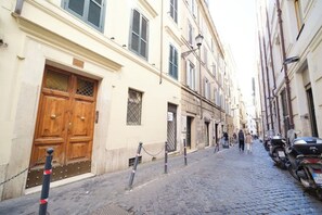 A cobblestone street with buildings, a wooden door, and parked motorcycles. - BuddyRent - Dadada - Trevi - 8 ospiti (Roma)