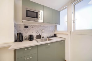 A kitchen with a microwave, sink, and green cabinets. - BuddyRent - Dadada - Trevi - 8 ospiti (Roma)