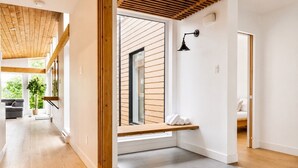 Et moderne interiør med træloft, en bænk ved et vindue og et synligt badeværelse.