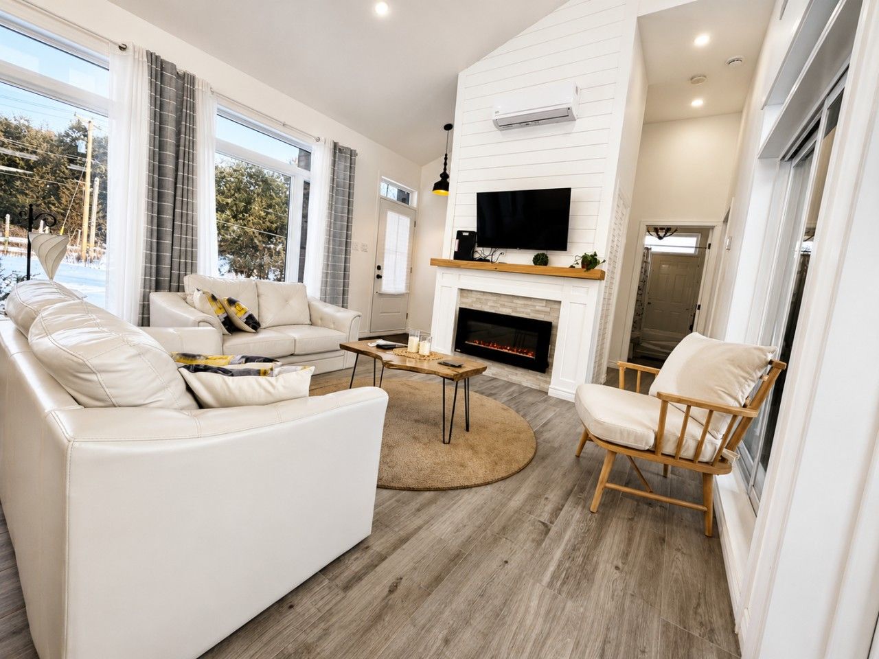 A modern living room with a fireplace, leather sofas, a wooden coffee table, and a TV mounted on the wall.