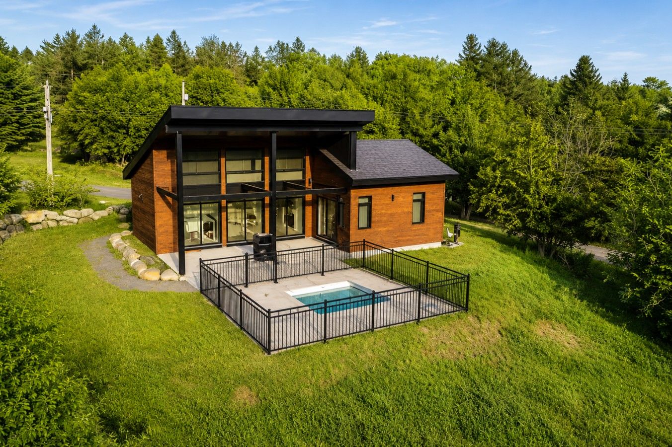 Ett modernt hus med en stor glasfasad, en terrass och en swimmingpool.