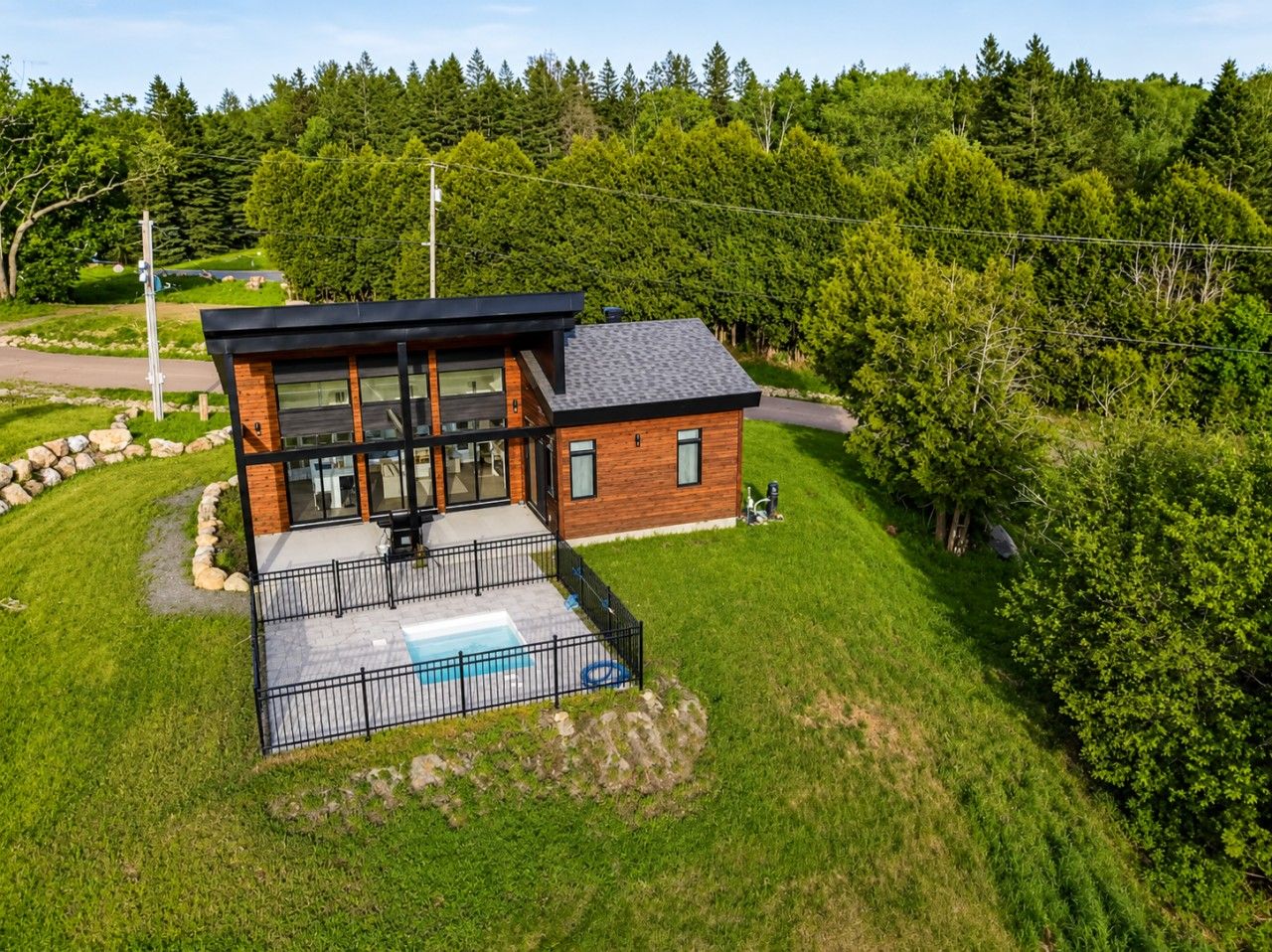 Een modern huis met een zwembad, omgeven door een verzorgd gazon en weelderige bomen.