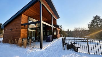 A modern building with a wooden facade and large windows, surrounded by snow.